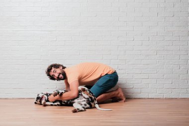 Genç sakallı adam beyaz tuğla karşı Dalmaçyalı köpekli duvar arka plan