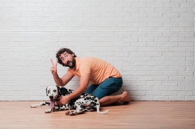 Genç sakallı adam beyaz tuğla karşı Dalmaçyalı köpekli duvar arka plan