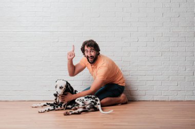 Genç sakallı adam beyaz tuğla karşı Dalmaçyalı köpekli duvar arka plan