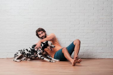 Genç sakallı adam beyaz tuğla karşı Dalmaçyalı köpekli duvar arka plan