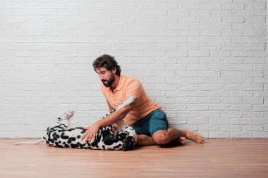 Genç sakallı adam beyaz tuğla karşı Dalmaçyalı köpekli duvar arka plan