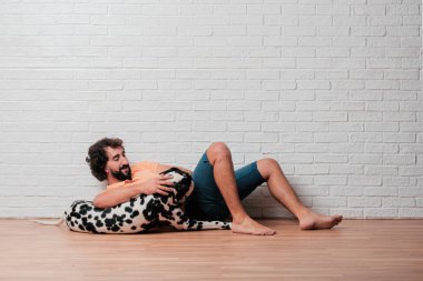 Genç sakallı adam beyaz tuğla karşı Dalmaçyalı köpekli duvar arka plan