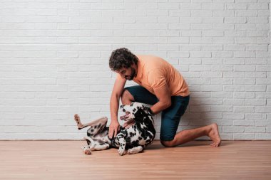 Genç sakallı adam beyaz tuğla karşı Dalmaçyalı köpekli duvar arka plan