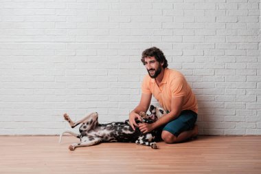 Genç sakallı adam beyaz tuğla karşı Dalmaçyalı köpekli duvar arka plan