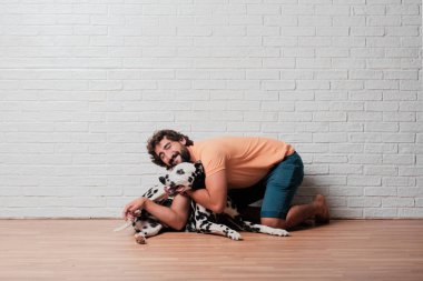 Genç sakallı adam beyaz tuğla karşı Dalmaçyalı köpekli duvar arka plan