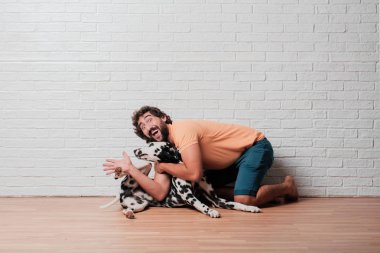 Genç sakallı adam beyaz tuğla karşı Dalmaçyalı köpekli duvar arka plan