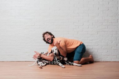 Genç sakallı adam beyaz tuğla karşı Dalmaçyalı köpekli duvar arka plan