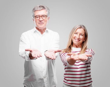 üst düzey serin karı koca bir nesne veya kavramı her iki el ile gösterilen, ikisi de ileriye dönük memnun bir ifadeyle gülümseyen.