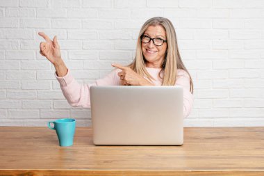 gülümseyen ve yukarı doğru nerede gazeteci bir kavram gösterebilir miyim yere doğru iki eliyle işaret eden üst düzey iş kadını.