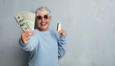 grunge çimento duvara kredi kartıyla kadın kıdemli serin. para ya da tasarruf kavramı.