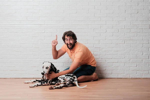 Genç sakallı adam beyaz tuğla karşı Dalmaçyalı köpekli duvar arka plan