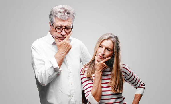 senior cool husband and wife With a confused and thoughtful look, looking sideways, thinking and wondering between different options.