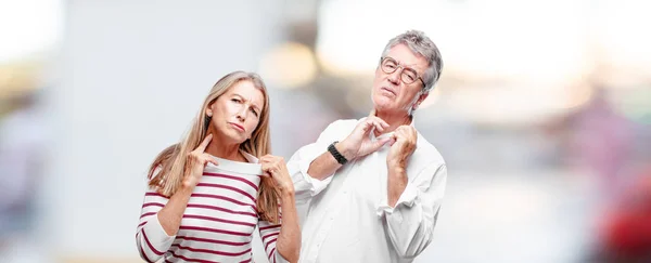 senior cool husband and wife with an anxious, stressed and nervous gesture, feeling under great pressure.