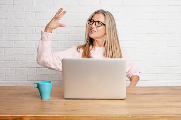 senior businesswoman smiling with a satisfied expression showing a small object or concept, holding it with single hand.