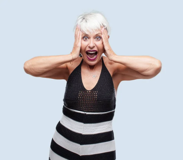 senior cool woman shouting with a crazy, amazed look of surprise, holding head with both hands.