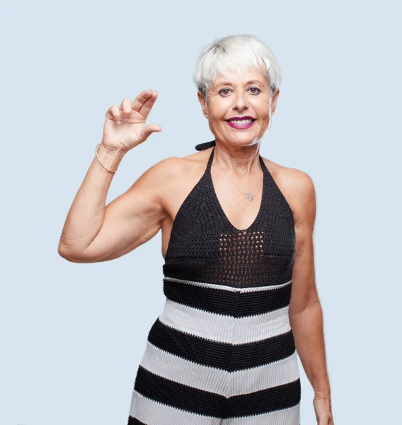 stock image senior cool woman smiling with a satisfied expression showing a small object or concept, holding it with single hand.