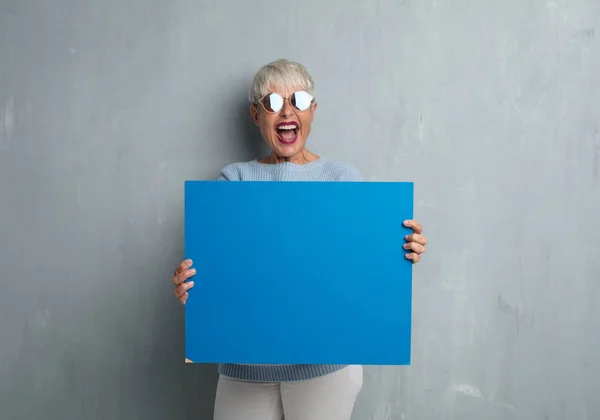 Senior Cool Woman Holding Empty Placard Grunge Cement Wall — Stock Photo, Image