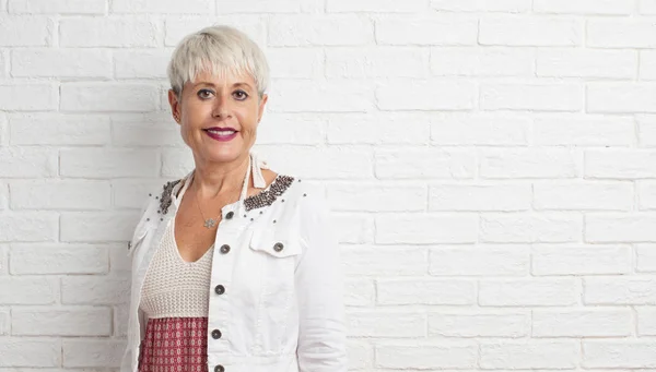 senior cool woman against white brick wall background