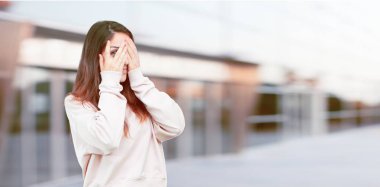 Genç güzel kız tam vücut bakmak iki eliyle gözlerini kapsayan korkmuş ve korkmuş bir ifade ile.