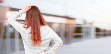 Genç güzel kız tam vücut arkadan görünüm, kalça, yandan diğer eliyle bir yere uzak mesafe bir nesneye işaret eden.