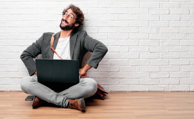 gurur, memnun ve mutlu bir görünüm ile katta kalça üzerinde iki eliyle sanki güvenle bakan bir meydan okuma oturan genç adam. Akimbo silah geniş bir gülümseme ile poz. Yan veya yan görünüm.