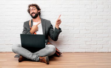 gülümseyen ve yan gazeteci bir kavram nerede gösterebilir yer doğru iki eliyle işaret yerde oturan genç adam.