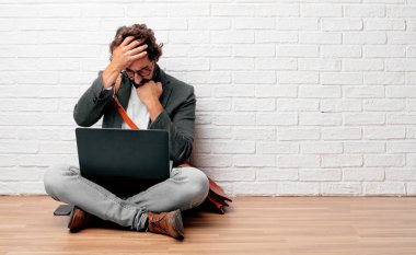 karışık ve düşünceli bir görünüm ile katta oturan, düşünme ve farklı seçenekler arasında merak yana doğru bakarak Genç adam.