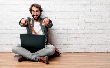 Sen tercih mutlulukla gülümseyerek ve ileriye dönük iki elle, yerde oturan genç adam.