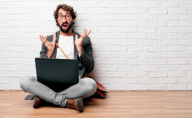 bir deli ile bağırarak katta oturan genç adam hayran sürpriz, her iki el havada ile görünümünü.