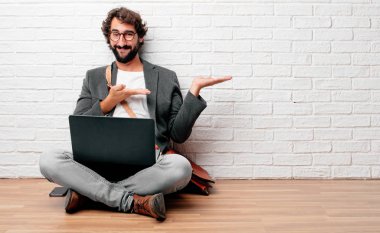 bir nesne veya kavramı her iki el ile gösterilen memnun bir ifade ile gülümseyen katta oturan genç adam.