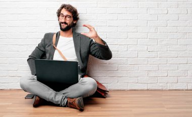 tek eliyle tutarak bir küçük bir nesne veya kavramı, gösterilen memnun bir ifadeyle gülümseyen katta oturan genç adam.