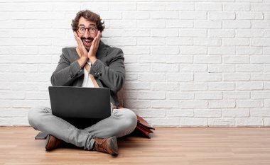 ifade ile mutlu bir katta oturan genç adam şaşırttı, gözleri geniş açık ve geniş gülümseme, yüz iki eliyle tutarak.