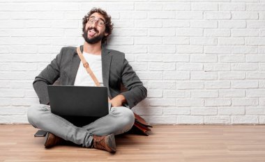 Şaka, komik, aptalca ve oynak bir ifadeyle dil yapışkanlık dışarı, bir aptal gibi seyir katta oturan genç adam.