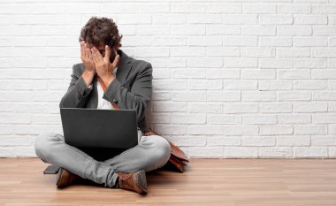 korkmuş, zemin üzerinde oturan genç adam gözleri iki eliyle bakmak kapsayan ifade, korkuttu.