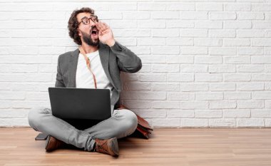 deli gibi yüksek sesle bağırarak, sinirli bir ifade ile el ile arama, büyük bir duyuru iletişim katta oturan genç adam. Yanal veya yan görünüm.