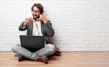 bir telefon görüşmesi jest veya işareti, gurur, mutlu, memnun bir bakışla yapma katta oturan genç adam; ileri doğru işaret eden bir gülümseme ile iletişim sunan.