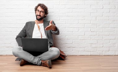 iyi bir anlaşma kapanış veya selamlama ve sizi karşılayan bir el sıkışma, sunan bir gülümseyen, kendine güvenen, gurur, memnun ve samimi ifadesiyle katta oturan genç adam.