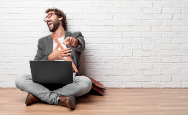 Genç adam zor bir şeye gülüyor komik ve işaretleme size doğru göbek diğer elinizle tutarken katta oturan komik fıkralar ile iyi vakit geçiriyor.