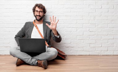 Beş parmaklı, avuç ile sayılması kat gülümseyerek oturan ve memnun ve mutlu, arayan genç adam.