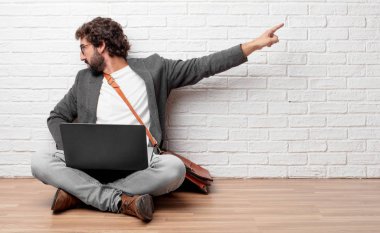 görünümü, el kalça yere geri oturmak ve tırmalamak baş diğer eliyle sanki karışık ya da düşünceli bir genç adam.