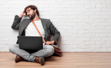 Genç adam yere geri görünüm, kalça, el oturma diğer eliyle bir yere uzak mesafe bir nesneye işaret.