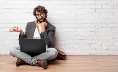 Genç adam yerde oturuyor. 