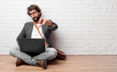 Genç adam bir, ciddi, muhalif ile yerdeki başparmak ile sert ifade onaylanmama içinde oturarak.