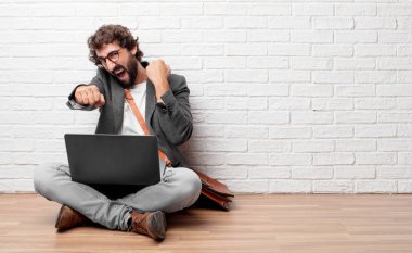 Genç adam bir öfkeli, agresif ve tehditkar poz, dövüş için hazır ile katta oturan öfkeyle ve kati yumruk gösterilen.