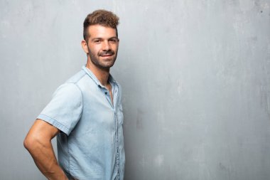 yakışıklı delikanlı her ikisi ile gurur, memnun ve mutlu bir görünüm ile güvenle bakan bir meydan okuma sanki kalçalarına, eller. Akimbo silah geniş bir gülümseme ile poz. Yan veya yan görünüm.