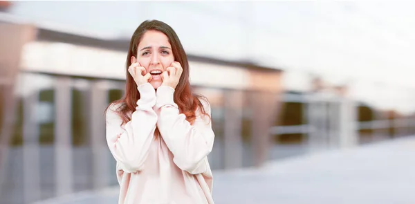 young pretty girl full body with a stressed gesture, with both hands clenched half covering face.