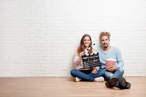 Šťastný Mladý Pár Sedí Podlaze Držení Popcornu Klapka — Stock fotografie