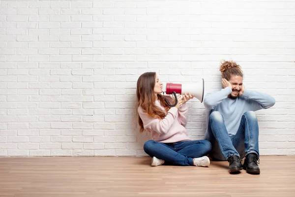 幸福的年轻夫妇坐在他们的新房子的地板上 拿着扩音器 爱和搬家的概念 — 图库照片