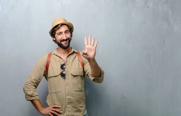 young traveler man or tourist smiling and looking satisfied and happy, counting number four with fingers.