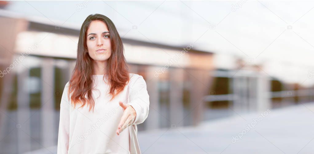 young pretty girl full body with a serious, confident, proud and stern expression offering a handshake, closing a deal, or greeting and welcoming you.